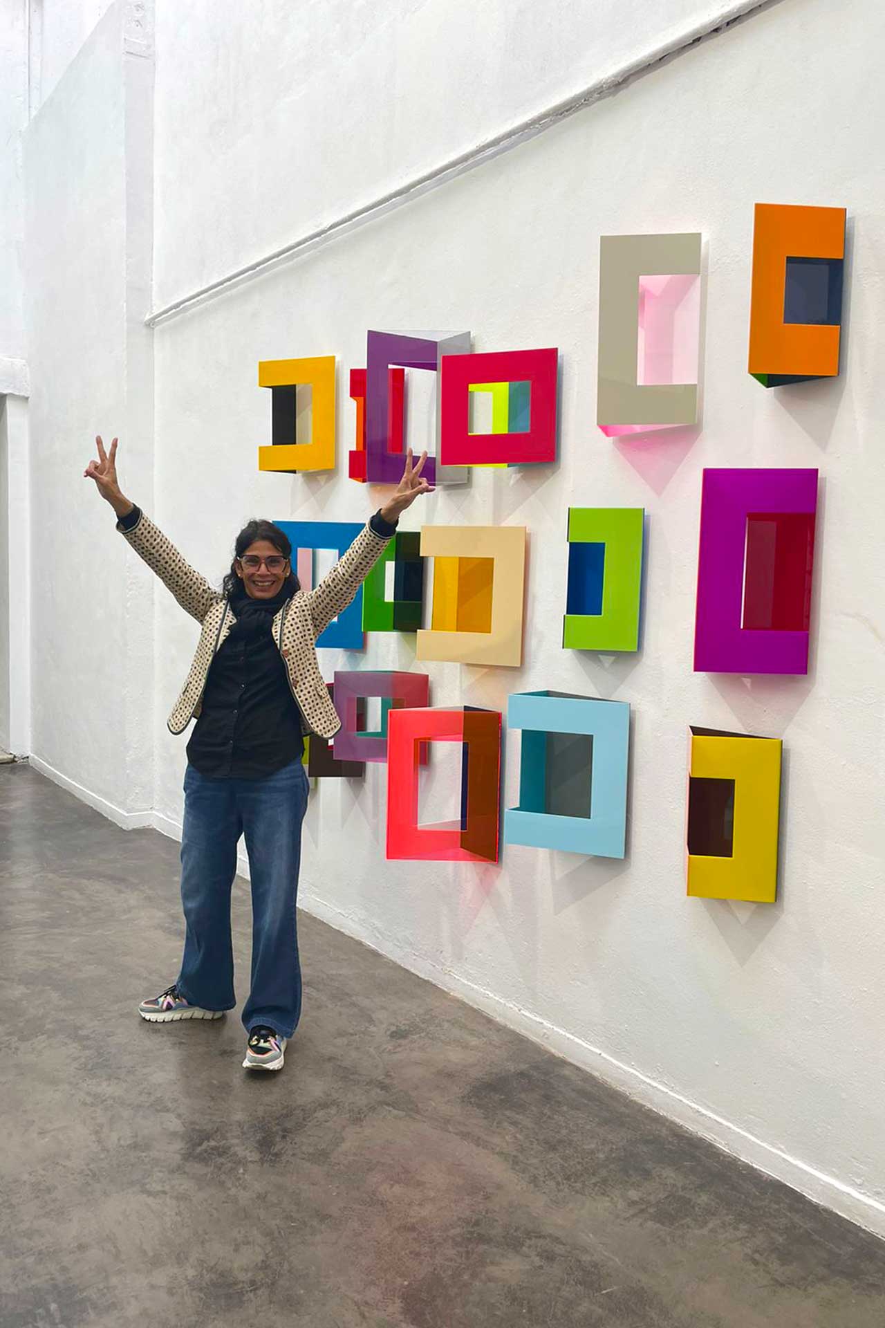 Retrato de la artista Patricia Quevedo en frente de sus obras, en una galeria en Bogotá